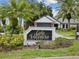 A neighborhood sign with lush landscaping reads 'Lake Valencia East' with a home in the background at 5110 Lake Valencia E Blvd, Palm Harbor, FL 34684