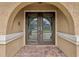 Elegant arched double front doors with decorative glass and a brick walkway create a welcoming entrance to the home at 5110 Lake Valencia E Blvd, Palm Harbor, FL 34684