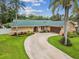 Stunning Florida home featuring a curved driveway, lush landscaping, and a beautiful green roof at 5110 Lake Valencia E Blvd, Palm Harbor, FL 34684