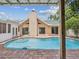 Inviting in-ground pool with brick patio and view of the home's rear exterior at 5110 Lake Valencia E Blvd, Palm Harbor, FL 34684