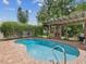 Relaxing backyard pool featuring a brick surround and an outdoor fireplace with a covered pergola at 5110 Lake Valencia E Blvd, Palm Harbor, FL 34684