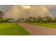 Beautiful home featuring a long drive, pristine lawn, and a vibrant rainbow in the background at 9016 Falcon Ct, Venice, FL 34293