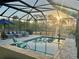Screened-in pool area with comfortable seating, BBQ, and scenic view of trees and sunrise at 9016 Falcon Ct, Venice, FL 34293
