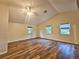 Bright bedroom featuring wood floors, a vaulted ceiling, a ceiling fan, and three large windows at 10928 Echo Loop, New Port Richey, FL 34654
