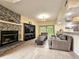Warm living room with stone fireplace, tile floors, and an open layout to the kitchen at 10928 Echo Loop, New Port Richey, FL 34654