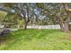 Wide backyard featuring mature trees, white fence, and covered patio attached to the house at 4410 Lurline Cir, Tampa, FL 33610