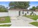 View of a charming single-story home with white fence, stone accent wall and attached garage at 4410 Lurline Cir, Tampa, FL 33610