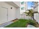 This beautiful backyard features an iron fence, small palms, and green grass at 15405 Gulf Blvd # B1, Madeira Beach, FL 33708