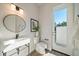 Modern powder room with white vanity, oval mirror, and private access to backyard at 2011 Belleair Rd, Clearwater, FL 33764