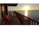 Gorgeous sunset view over the ocean from the condo balcony with red chairs, creating a peaceful ambiance at 15316 Gulf Blvd # 604, Madeira Beach, FL 33708
