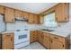 Efficient kitchen featuring wood cabinets and white appliances at 3423 Eisenhower Dr, Holiday, FL 34691