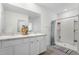 Bright bathroom featuring a double vanity, large mirror, and a walk-in shower with modern fixtures at 10913 Trailing Vine Dr, Tampa, FL 33610