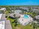 Aerial view featuring a sparkling pool, lush tropical landscaping, clubhouse and tennis courts at 12300 Vonn Rd # 3204, Largo, FL 33774