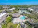 Aerial view featuring a sparkling pool, lush tropical landscaping, clubhouse, tennis courts and shuffleboard at 12300 Vonn Rd # 3204, Largo, FL 33774