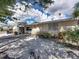 Tan single story house with a blue door, gravel driveway, and lush landscaping at 16003 2Nd E St, Redington Beach, FL 33708