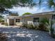Tan single story house with a blue door, gravel driveway, and well-maintained landscaping at 16003 2Nd E St, Redington Beach, FL 33708