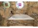 Stylish bathroom showcasing a soaking tub surrounded by travertine walls at 761 Soundview Dr, Palm Harbor, FL 34683