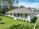 Back exterior featuring a covered patio, well-kept lawn, and beautiful landscaping at 4780 Majestic Hills Loop, Brooksville, FL 34601