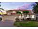Stunning two-story home with tile roof, three-car garage, and beautiful landscaping at dusk at 17371 Kennedy Dr, North Redington Beach, FL 33708