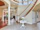 Elegant two-story entryway with curved staircase, hardwood floors, and views to living areas at 17371 Kennedy Dr, North Redington Beach, FL 33708