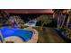 Night view of outdoor pool area and dock featuring palm trees, outdoor lighting, and waterfront views at 516 Belle Isle Ave, Belleair Beach, FL 33786