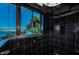 Bathroom shower with dark tile, accented by brass fixtures, and a window showcasing the waterfront view at 516 Belle Isle Ave, Belleair Beach, FL 33786