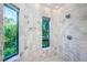 Marble bathroom highlighting a tiled walk-in shower and greenery visible through the windows at 516 Belle Isle Ave, Belleair Beach, FL 33786