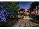 Night view of a brick home with a patterned driveway, lush landscaping, and outdoor lighting at 516 Belle Isle Ave, Belleair Beach, FL 33786