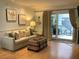 Living room with sliding door to deck, sofa and wicker coffee table at 19930 Gulf Blvd # 1A, Indian Shores, FL 33785