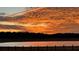 Vibrant sunset colors reflected on a tranquil lake with a grassy bank at 3136 Neff Lake Rd, Brooksville, FL 34602