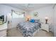 Inviting bedroom with a queen-sized bed, white furniture, patterned bedding, and soft natural light from the window at 4136 Rhone Dr, New Port Richey, FL 34655