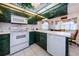Bright kitchen with unique green cabinets, white appliances, and a breakfast bar overlooking the dining area at 4136 Rhone Dr, New Port Richey, FL 34655