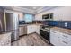 Well-lit kitchen with white cabinets, granite countertops, stainless appliances and blue tiled backsplash at 1868 Shore S Dr # 410, South Pasadena, FL 33707