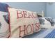 Decorative 'Beach House' pillow sitting on a blue and white striped bedspread at 20204 Gulf Blvd # 9, Indian Shores, FL 33785