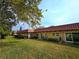 Exterior view of building with tile roof and green lawn at 1701 Pinehurst Rd # 26E, Dunedin, FL 34698