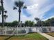 Community pool area with white picket fence and tropical landscaping at 1701 Pinehurst Rd # 26E, Dunedin, FL 34698