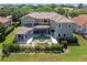 Aerial view of a home featuring a pool, spa, covered patio, and balcony overlooking a green backyard at 898 Skye Ln, Palm Harbor, FL 34683
