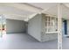 Spacious carport area with a covered roof, grey concrete flooring, and a protective barrier on the left side at 2305 N Tampania Ave, Tampa, FL 33607