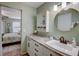 Bathroom with a white vanity, storage cabinet, circular mirror, and view into bedroom at 103 Cypress Pond Rd # 103, Palm Harbor, FL 34683