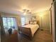Cozy bedroom featuring a ceiling fan, wood floors, and a sliding glass door leading to the outside at 103 Cypress Pond Rd # 103, Palm Harbor, FL 34683