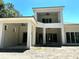 Stunning modern exterior featuring a covered patio with ceiling fan, large windows and a two-story open balcony at 8418 Fussell Dr, Wesley Chapel, FL 33545