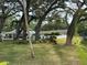 Expansive backyard featuring mature trees, a tranquil lake, and inviting outdoor seating areas at 821 Deleon Ct # 103, Dunedin, FL 34698