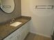Bathroom features a granite countertop with white vanity and decorative mirror at 940 Virginia St # 107, Dunedin, FL 34698