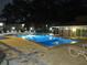 Night view of a community swimming pool with lounge chairs and surrounding lighting at 940 Virginia St # 107, Dunedin, FL 34698