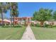 Charming two-story condo with a pathway through the manicured lawn, palm trees, and colorful flowers at 9543 86Th Ave # 9543, Seminole, FL 33777