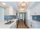 Modern kitchen with white cabinets, blue tile backsplash and stainless steel appliances at 550 Johns Pass Ave, Madeira Beach, FL 33708