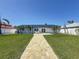 Waterfront home featuring a lawn, patio, and modern lounge chairs at 240 N Julia Cir, St Pete Beach, FL 33706