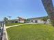Waterfront home with grass, dock, and patio with modern lounge chairs at 240 N Julia Cir, St Pete Beach, FL 33706