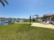 Waterfront home with grass, patio, two modern lounge chairs, and fenced dock at 240 N Julia Cir, St Pete Beach, FL 33706