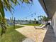 Waterfront home featuring an outdoor patio with modern string lights, green grass, and dock at 240 N Julia Cir, St Pete Beach, FL 33706